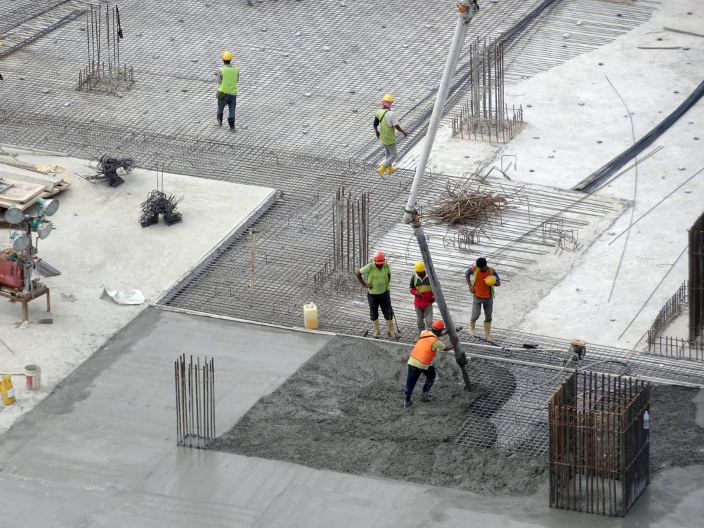 Trabalhadores aplicando concreto com bomba em laje de construção civil, mostrando processo moderno de concretagem.